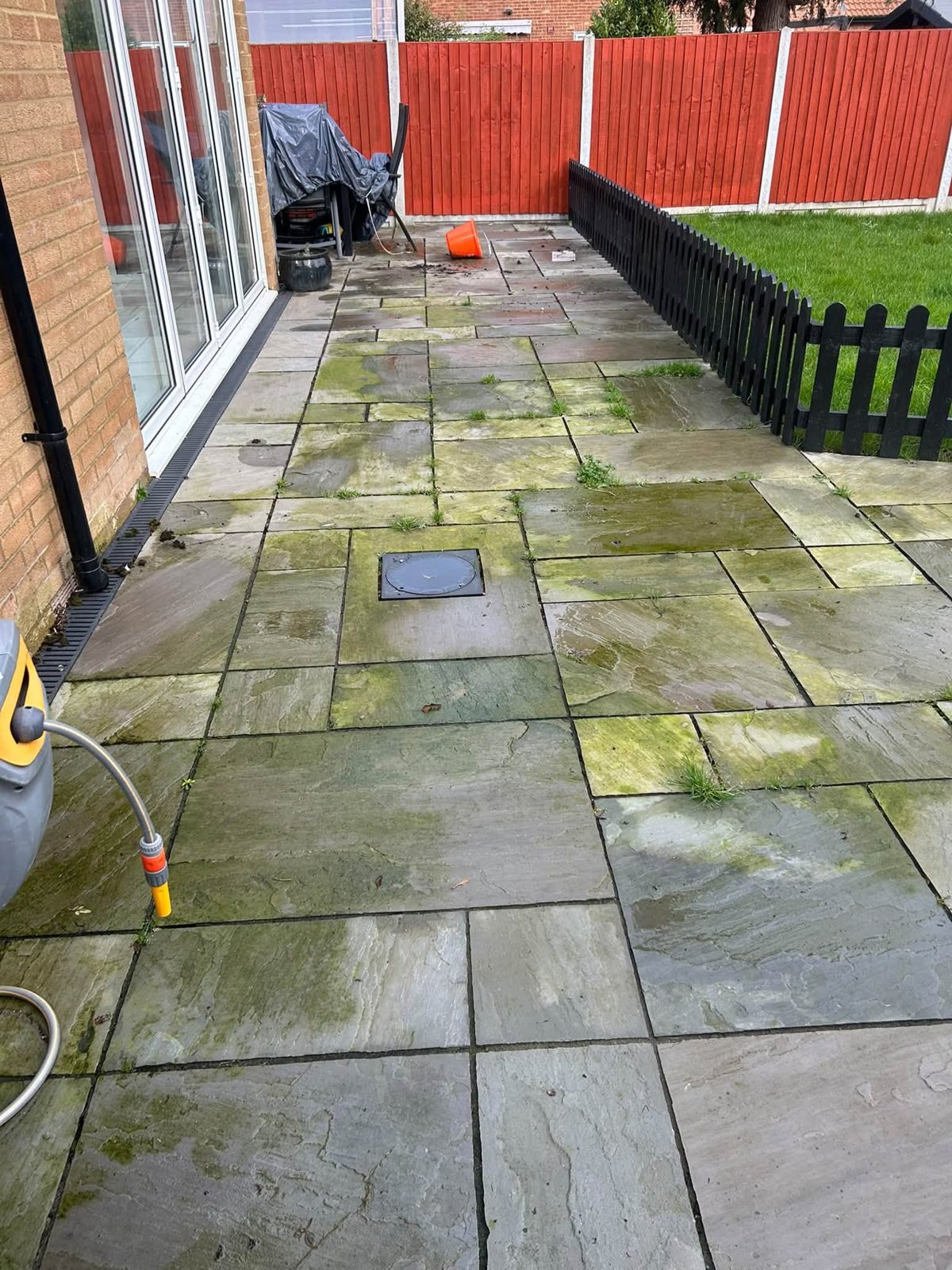 Before: a sandstone patio covered in green algae and weeds beside a red fence